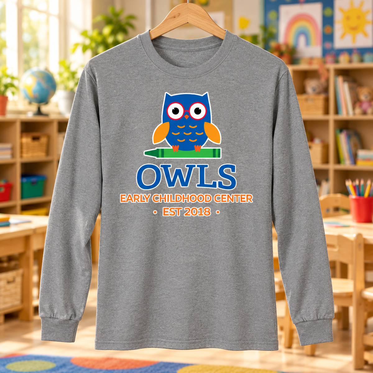 Early Childhood Center owls logo heather PC55LS long sleeve shirt in a classroom